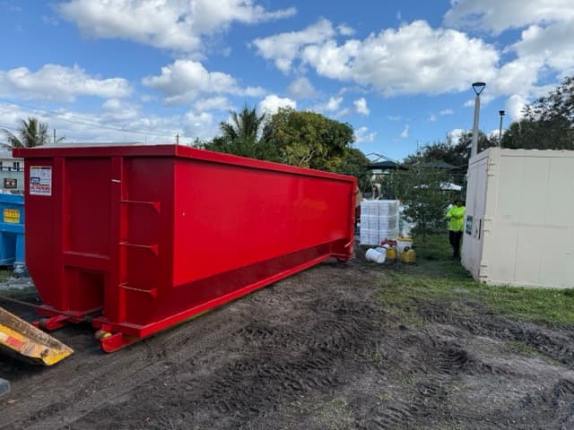 A large red roll-off dumpster on a job site