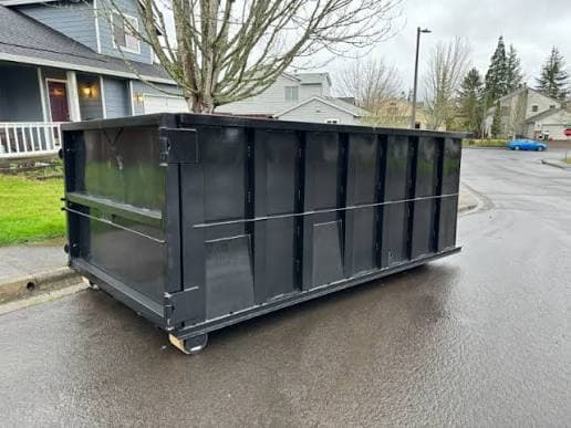 A dumpster placed on a residential street rather than a driveway