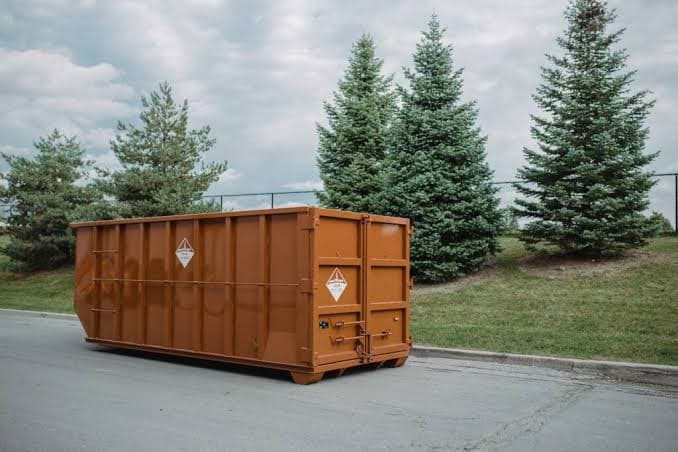 A roll-off dumpster delivered to a residential driveway, ready to be loaded
